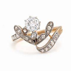 Diamantring af 18 kt. rød- og hvidguld prydet med brilliantslebet diamant med ældre slibning omkranset af rosenslebne diamanter. Str. 53. Ca. 1950.