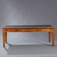 Skrivebord af egetræ, prydet med skæringer, plade med guldpræget grønt skind, sarg med tre skuffer. Ca. 1920. H. 78. L. 210. B. 100.